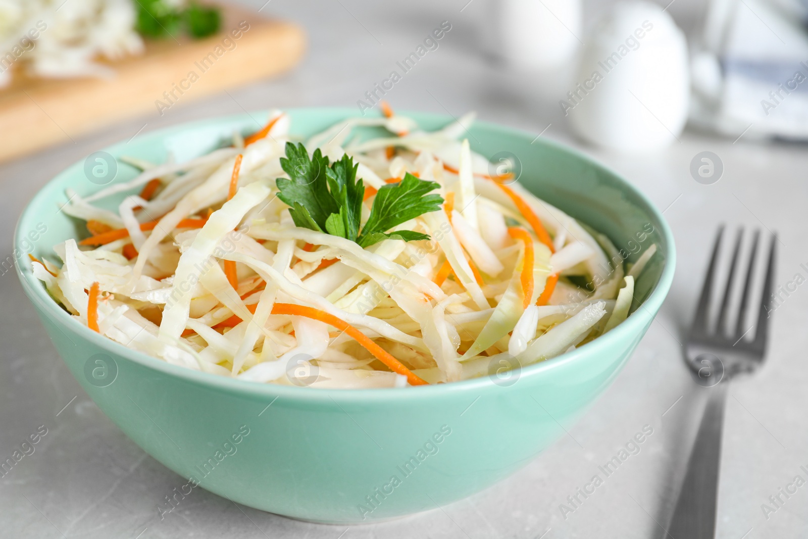 Photo of Tasty salad with cabbage and carrot on light grey table, closeup