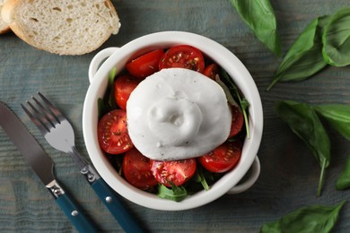 Photo of Delicious burrata cheese with tomatoes and basil served on grey wooden table, flat lay