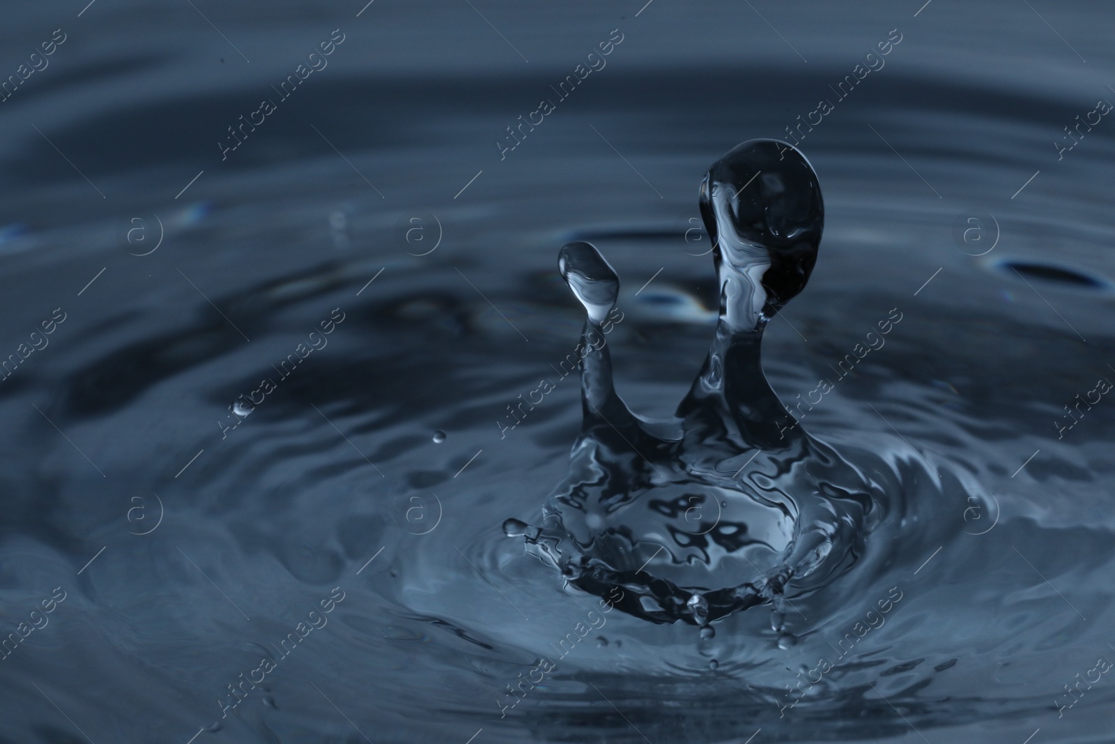 Photo of Splash of clear water with drops on dark blue background, closeup
