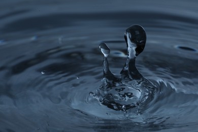 Photo of Splash of clear water with drops on dark blue background, closeup