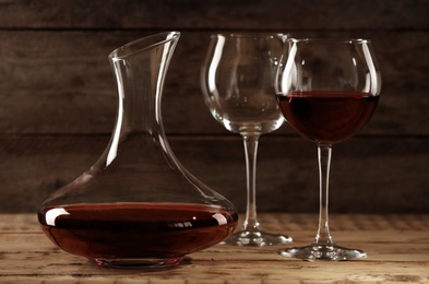Photo of Elegant decanter with red wine and glasses on wooden table