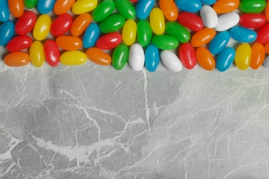 Delicious bright jelly beans on stone background, top view. Space for text