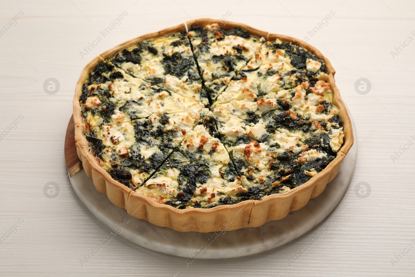 Photo of Delicious homemade spinach quiche on white wooden table