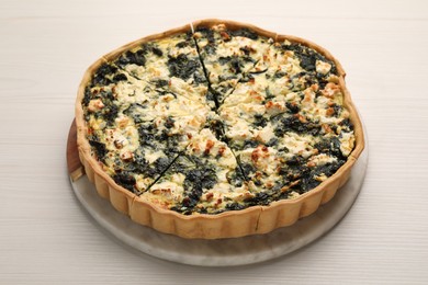 Delicious homemade spinach quiche on white wooden table