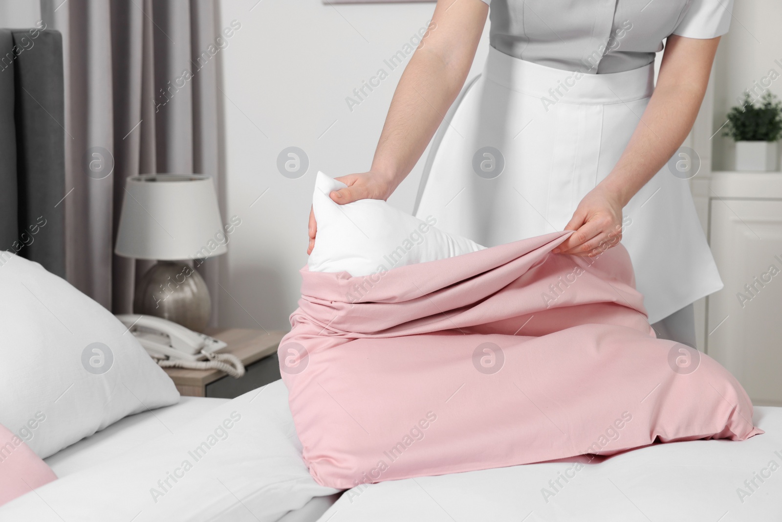 Photo of Maid making bed in hotel room, closeup