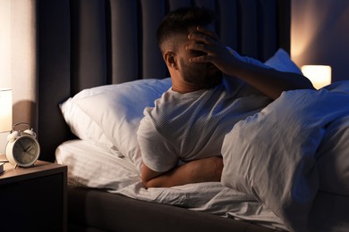 Photo of Man covering face with hand in bed. Insomnia problem