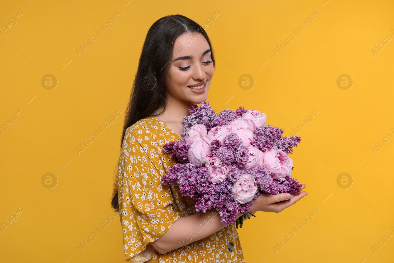 Photo of Beautiful woman with bouquet of spring flowers on yellow background