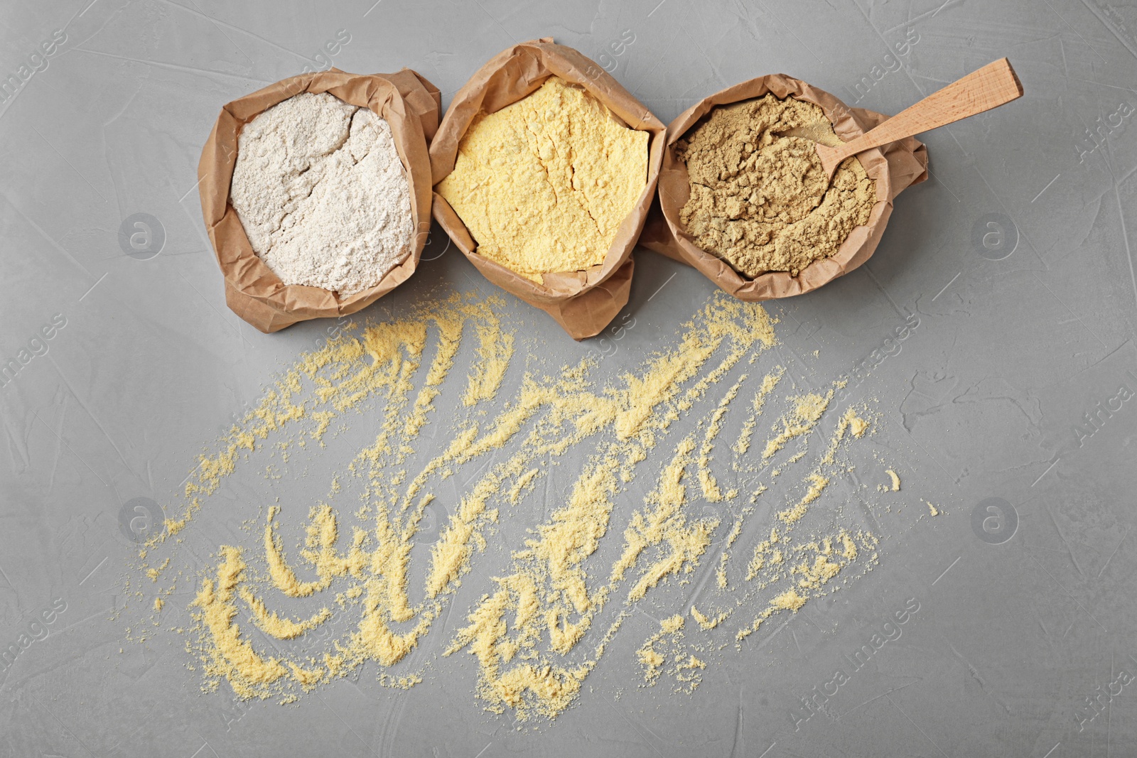 Photo of Paper bags with different types of flour on gray background