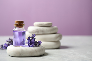 Photo of Stones, bottle of essential oil and lavender flowers on marble table. Space for text