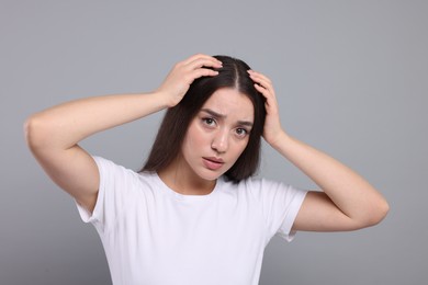 Photo of Emotional woman with healthy hair on grey background. Dandruff problem