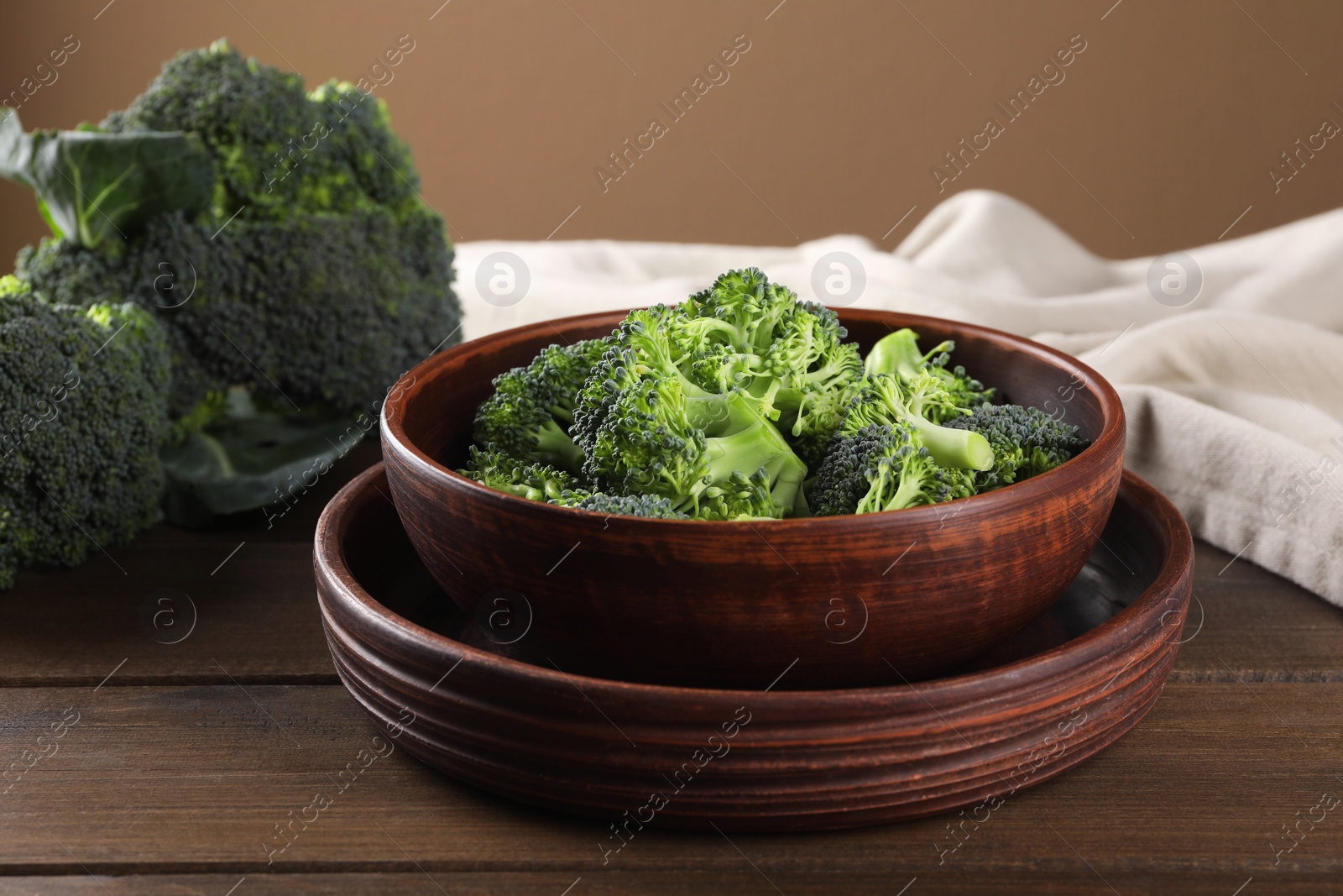 Photo of Bowl with fresh raw broccoli on wooden table