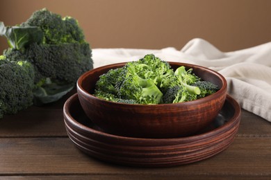 Bowl with fresh raw broccoli on wooden table