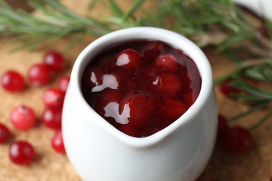 Photo of Cranberry sauce in pitcher and fresh berries on table, closeup