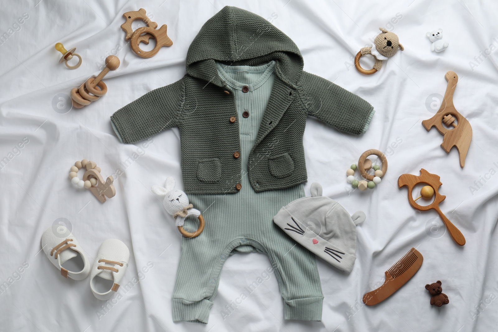 Photo of Flat lay composition with cute baby clothes and accessories on white bedsheet