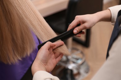 Photo of Stylist working with client in salon, closeup. Making haircut