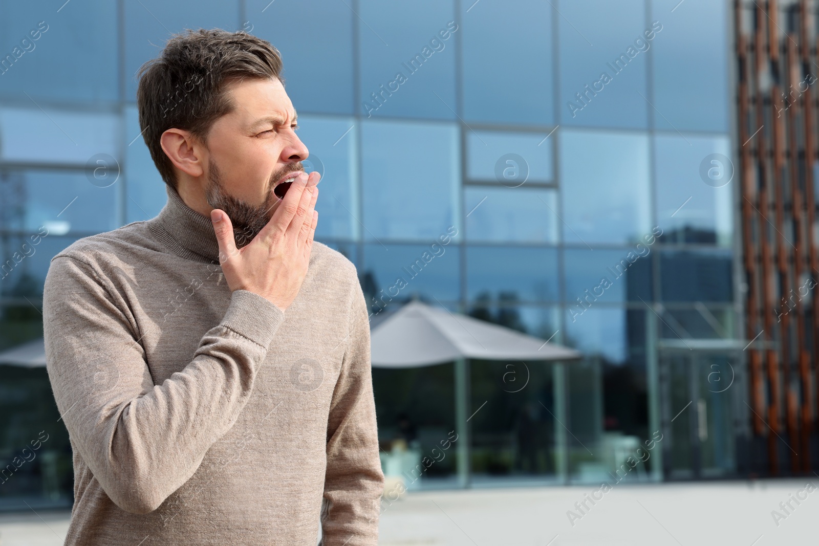Photo of Sleepy man yawning outdoors. Space for text