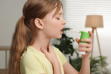 Photo of Little girl using throat spray at home