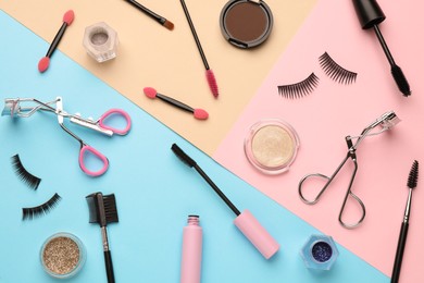 Flat lay composition with eyelash curler, makeup products and accessories on color background