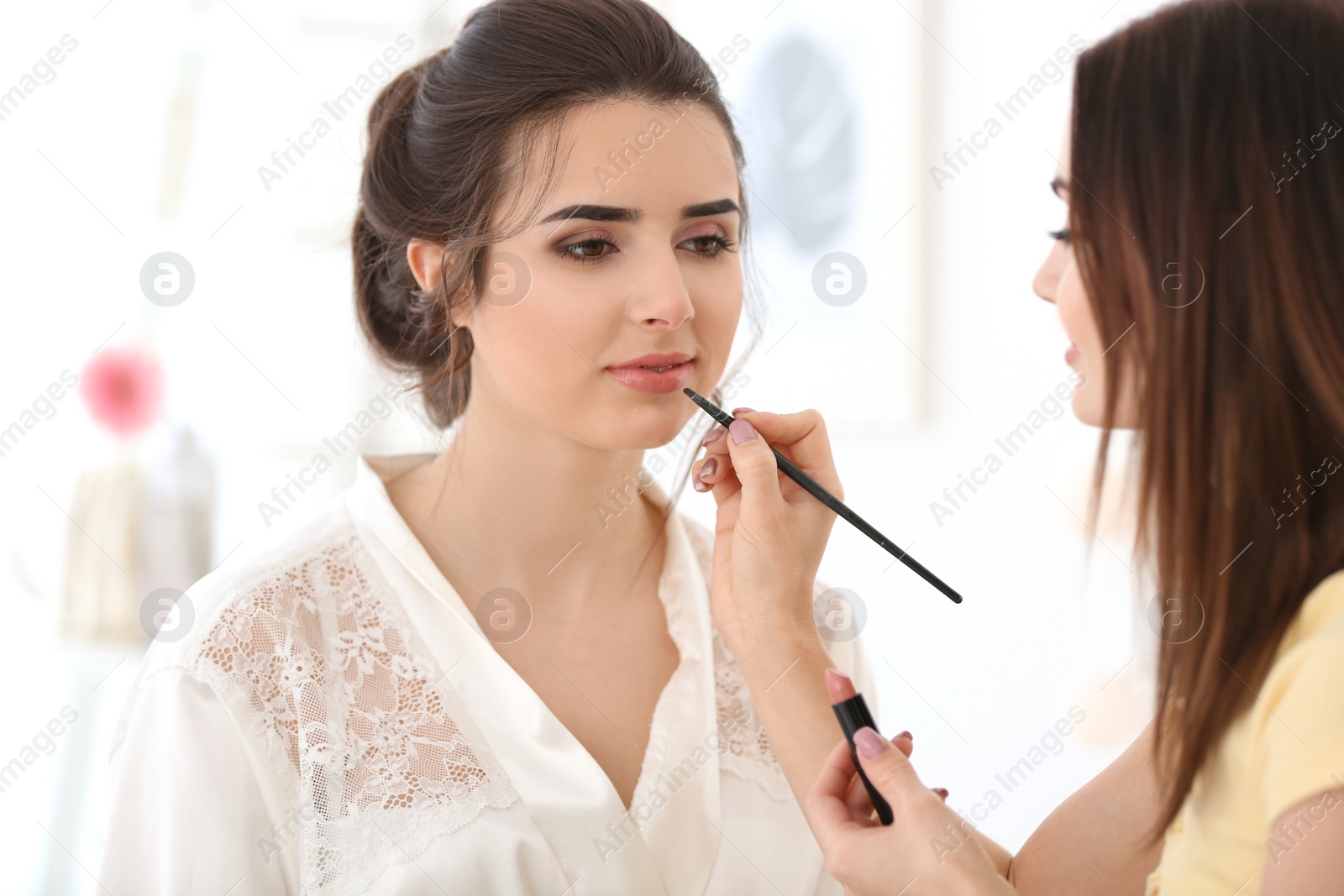 Photo of Professional makeup artist working with young woman in salon