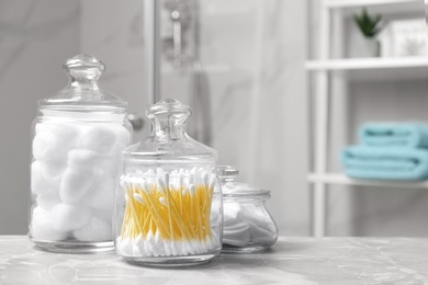 Photo of Cotton balls, swabs and pads on light grey marble table in bathroom