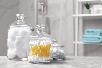 Cotton balls, swabs and pads on light grey marble table in bathroom