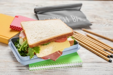 Photo of Lunch box with tasty sandwich on wooden table