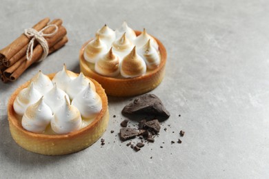 Photo of Tasty dessert. Tartlets with meringue served on light grey table. Space for text