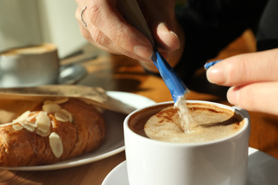 Woman with cup of fresh aromatic coffee at table in cafe