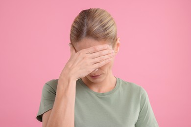 Photo of Embarrassed woman covering eyes on pink background