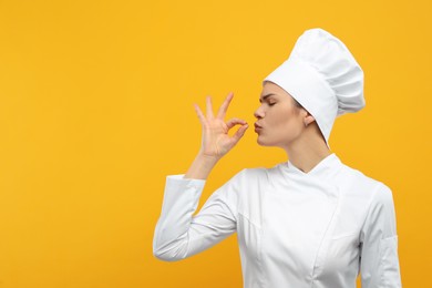 Photo of Female chef showing perfect sign on orange background. Space for text