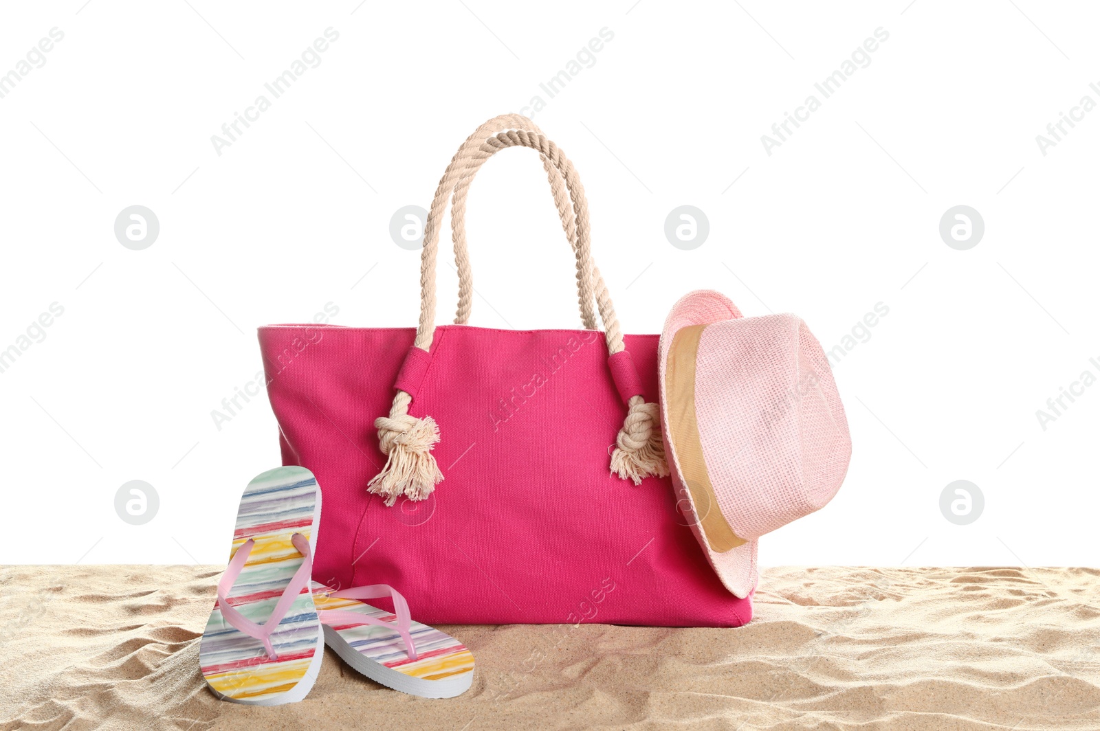 Photo of Stylish coral bag and beach accessories on sand against white background