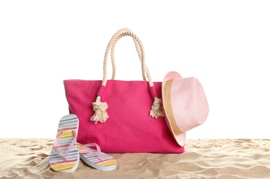 Stylish coral bag and beach accessories on sand against white background