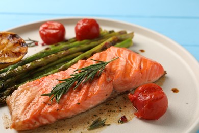 Tasty grilled salmon with tomatoes, asparagus and spices on table, closeup