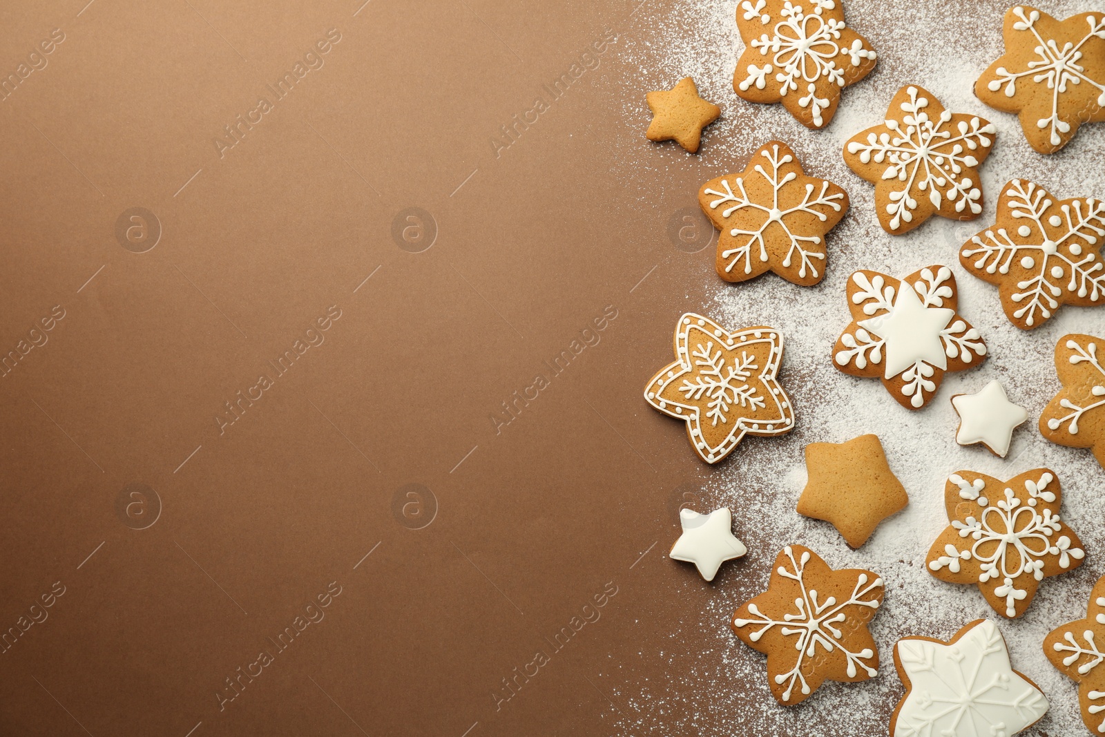 Photo of Tasty Christmas cookies with icing and powdered sugar on brown background, flat lay. Space for text