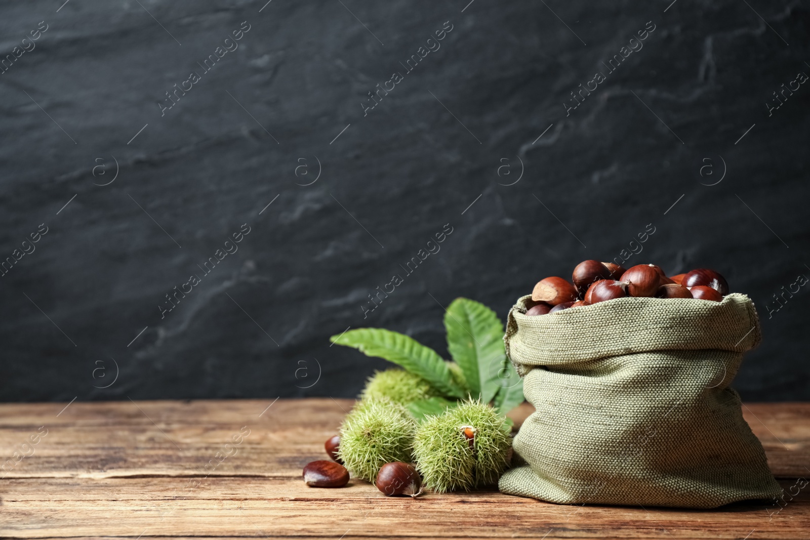 Photo of Fresh sweet edible chestnuts on wooden table. Space for text