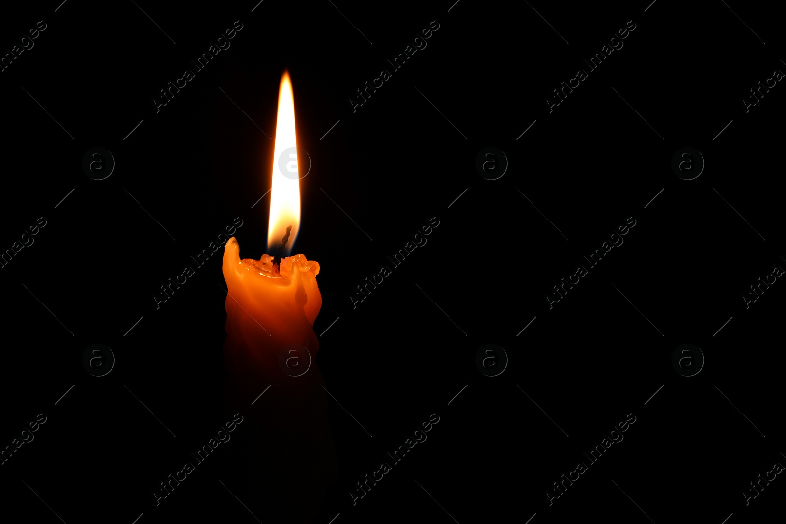 Photo of Burning candle on black background, closeup. Space for text