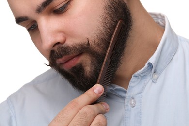 Handsome young man combing beard on white background, closeup