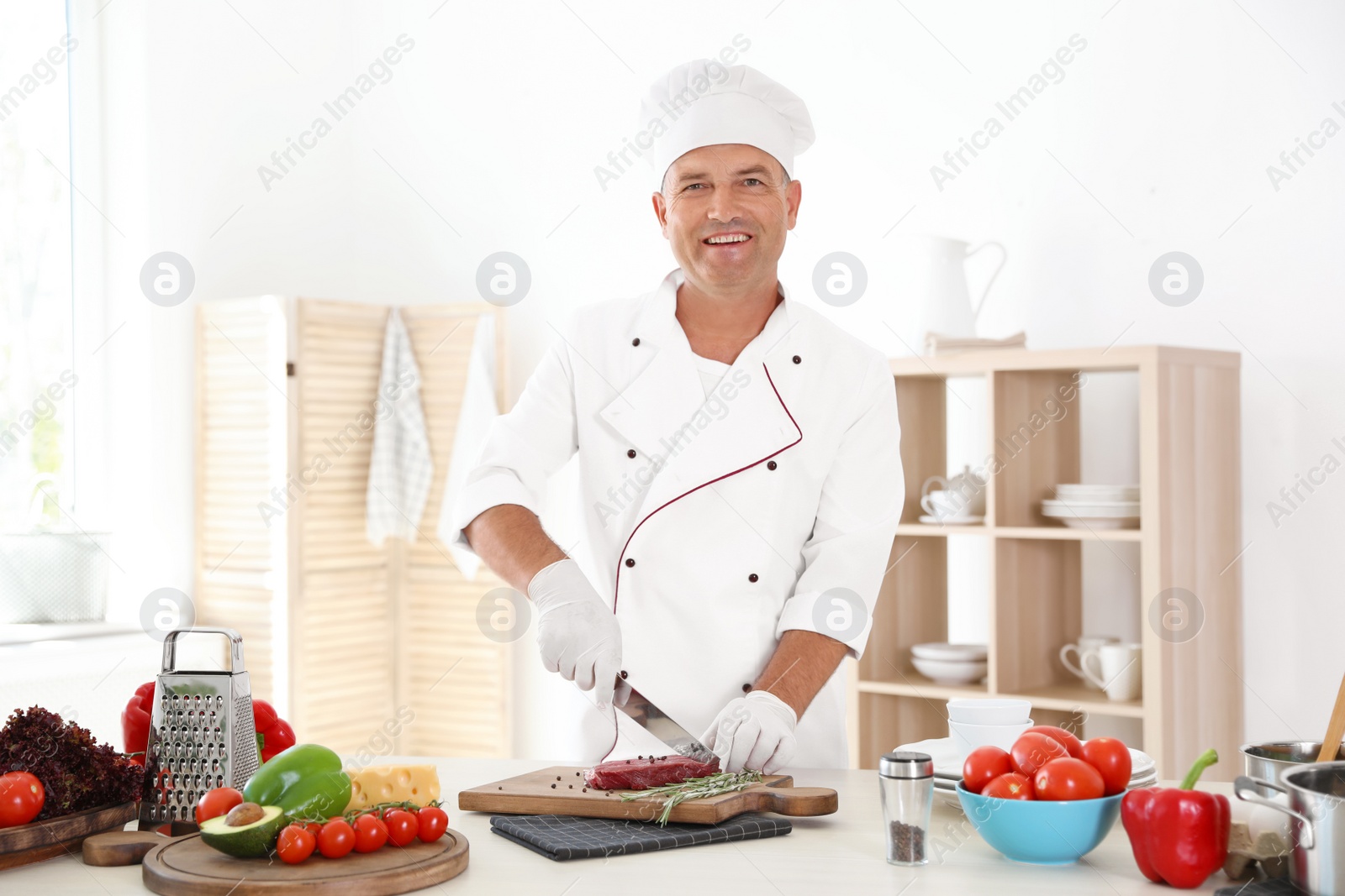 Photo of Professional chef cutting meat on table in kitchen