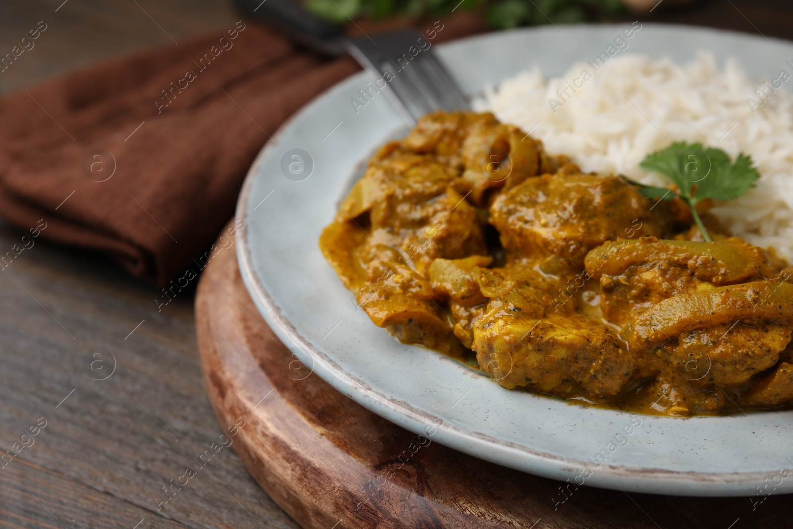 Photo of Delicious chicken curry with rice on wooden table, closeup