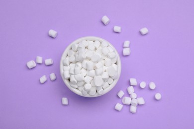 Delicious sweet marshmallows with bowl on purple background, flat lay