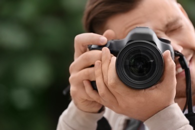 Photo of Male photographer with professional camera on blurred background. Space for text