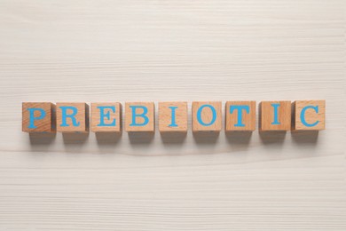 Word Prebiotic made of cubes with letters on wooden table, top view