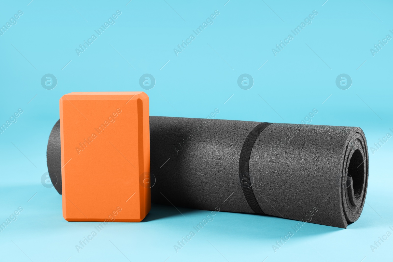 Photo of Exercise mat and yoga block on light blue background