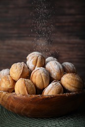 Photo of Bowl of delicious nut shaped cookies on wooden table