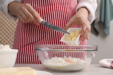 Making tasty baklava. Woman adding butter into bowl with flour at table, closeup