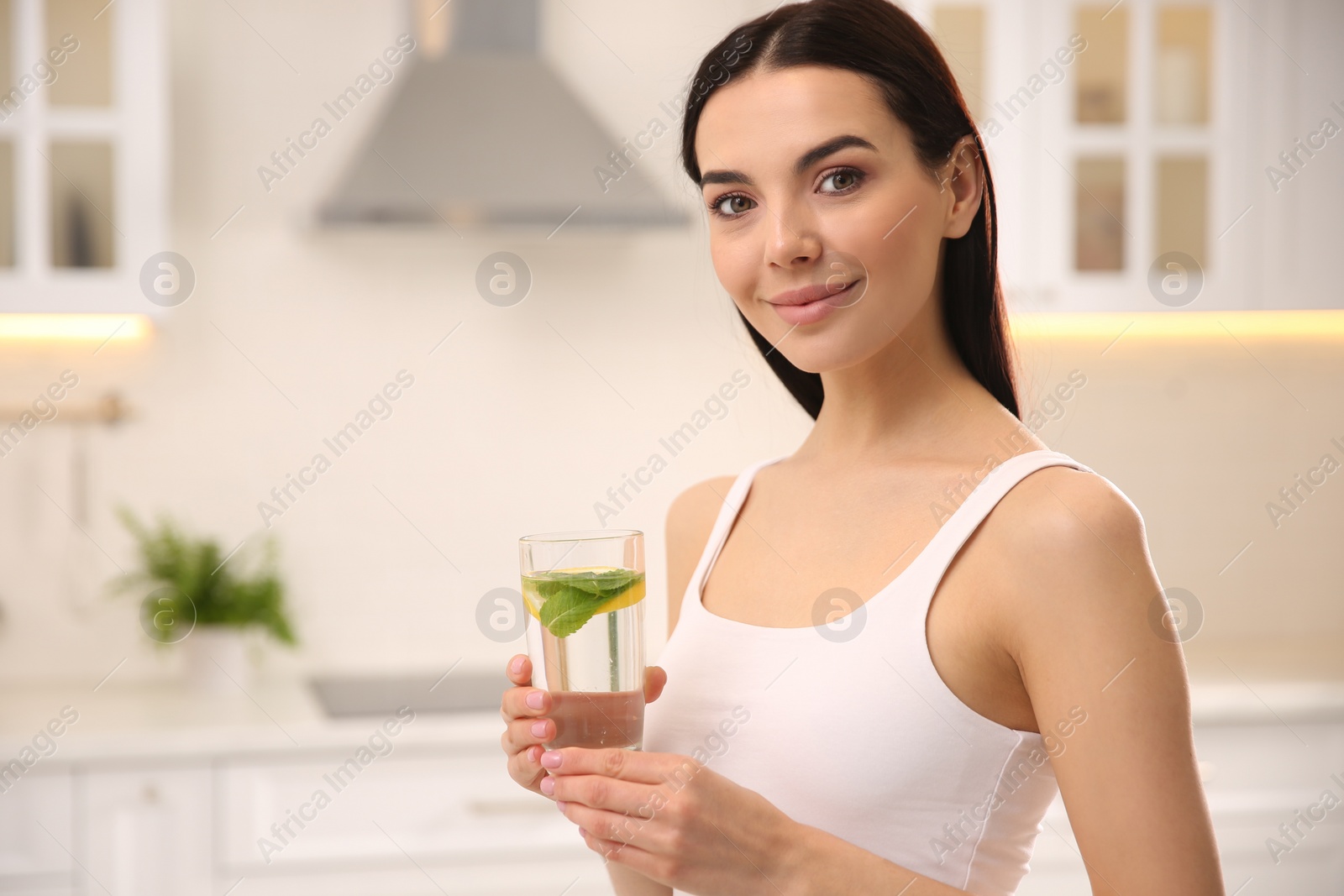 Photo of Young woman with glass of fresh lemonade at home