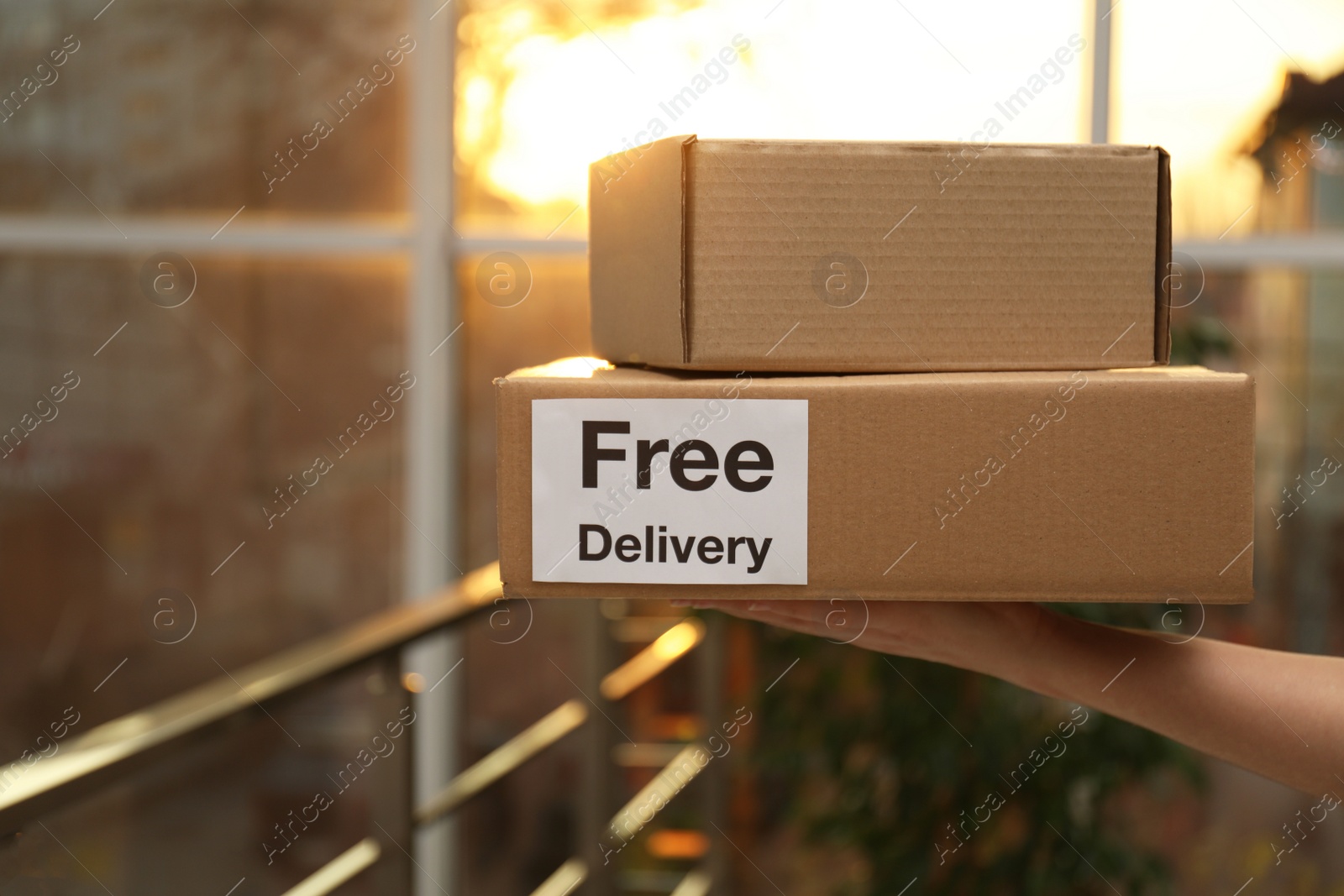 Photo of Woman holding parcels indoors, closeup. Courier service