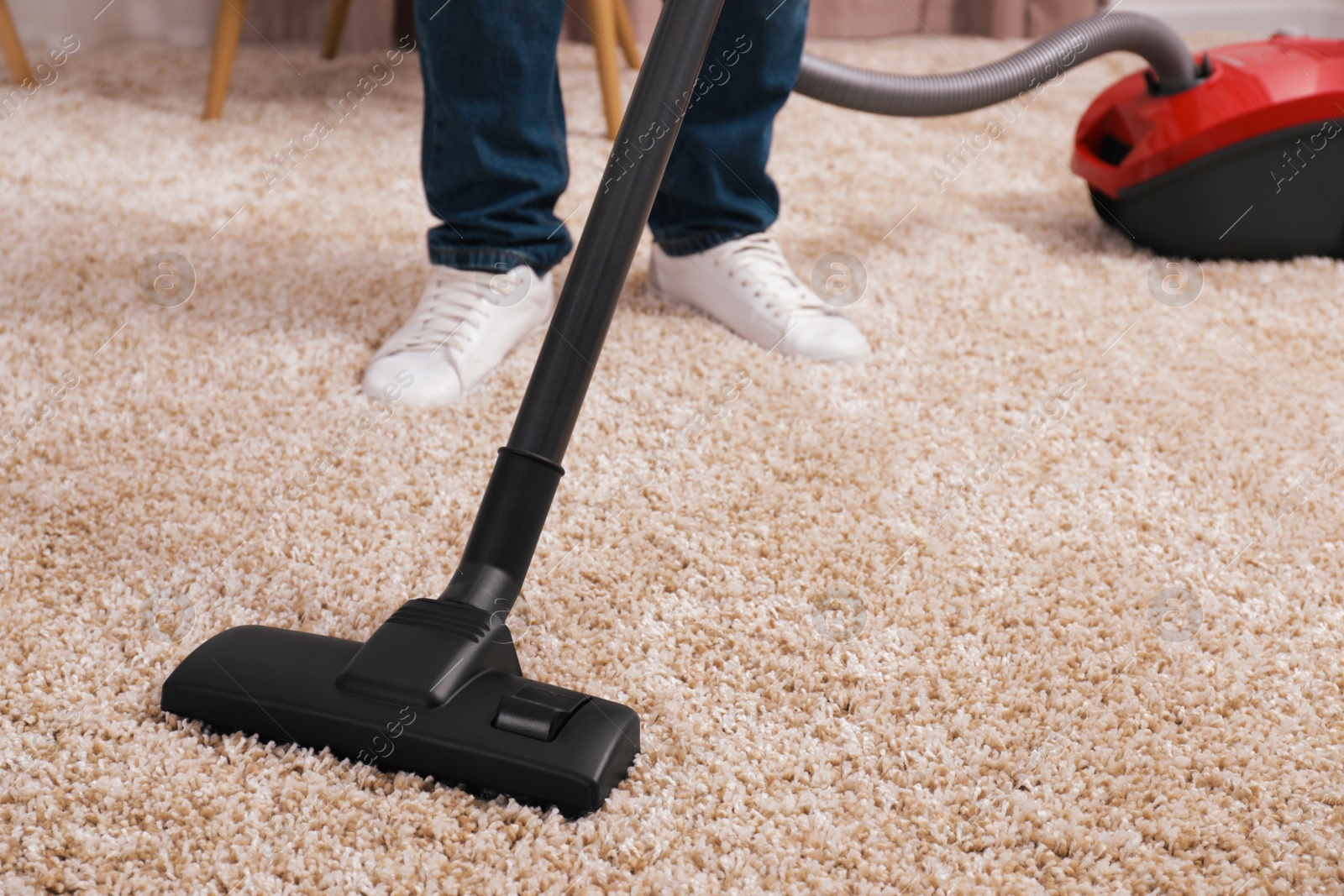 Photo of Man cleaning carpet with vacuum cleaner at home, closeup