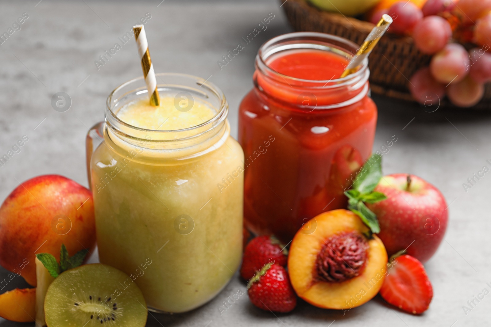 Photo of Delicious juices and fresh ingredients on grey table, closeup