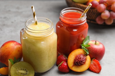 Photo of Delicious juices and fresh ingredients on grey table, closeup